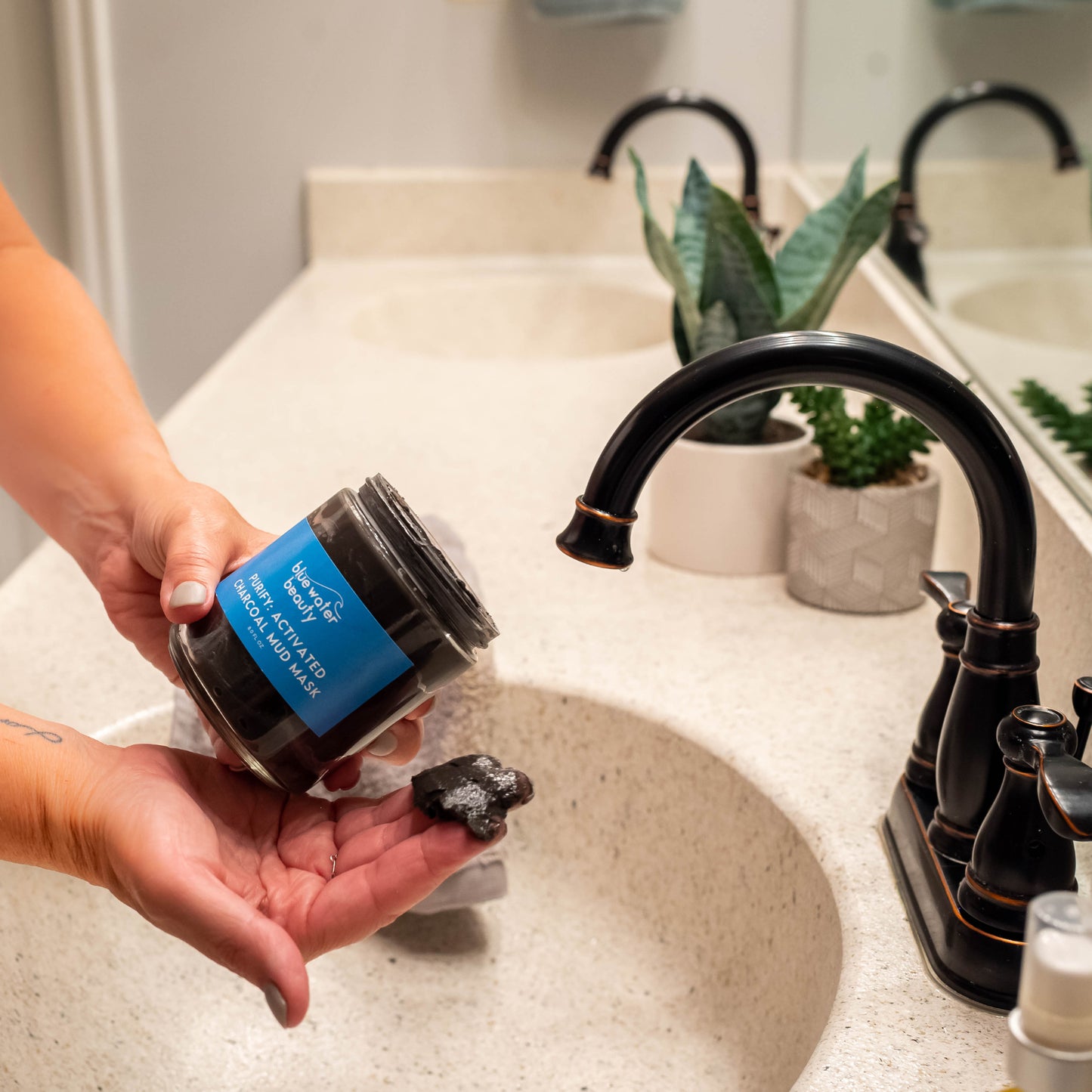 Person putting Activated Charcoal Mud Mask on hand.
